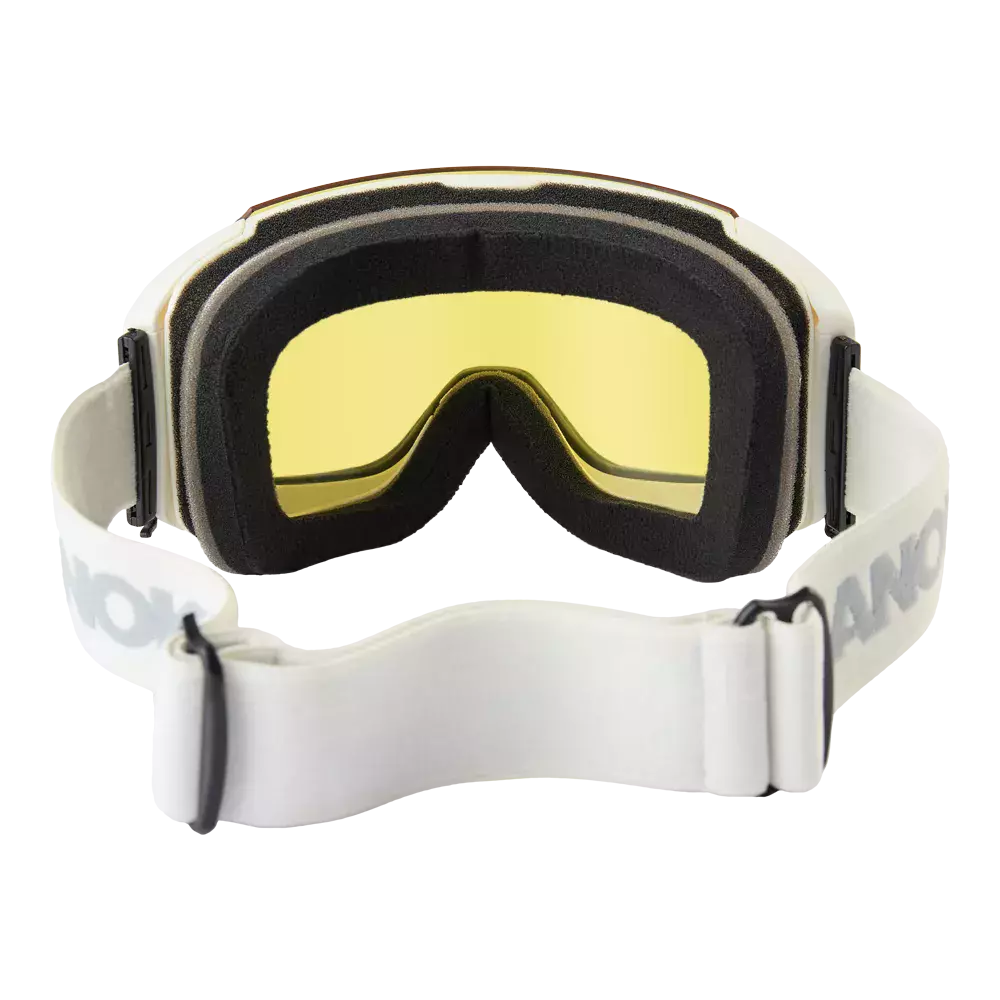 Et par skibriller med moderne og minimalistisk design: gultonet linse indrammet af sort, blødt skum for komfort og tætning. Den brede hvide elastiske rem med justerbar spænde sikrer stabil pasform, mens den buede form følger ansigtets konturer. Brillerne virker velegnede til udendørs aktiviteter som skiløb eller snowboarding, hvor beskyttelse mod vind og blænding er vigtig.