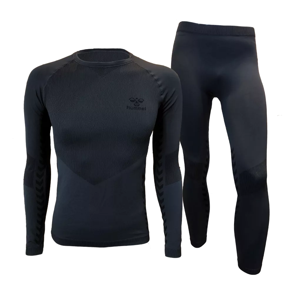 Et mørkt, tætsiddende sæt bestående af en langærmet overdel og matchende leggings i åndbart, ribstrikket materiale. Designet har anatomiske paneler og ekstra struktur ved ærmer og knæ for bevægelsesfrihed og isolering. Sættet virker termoaktivt og elastisk, velegnet som baselag til træning eller udendørs brug under kolde forhold. Simpelt, funktionelt og stilrent i en dæmpet sort nuance.