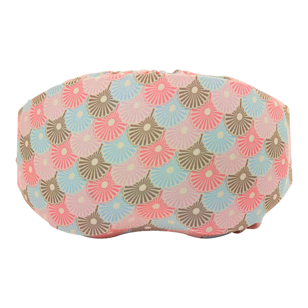 En blød søvnmaske med et gentaget mønster af små, halvcirkelformede blomster i lyserød, lyseblå, beige og brune toner. Stoffet har en let tekstur og et mat udtryk, der antyder bomuld eller linned. Maskens bløde konturer og dæmpede farvepalet giver et roligt, feminint indtryk, perfekt til afslapning eller rejser. Designet fremstår både dekorativt og funktionelt.