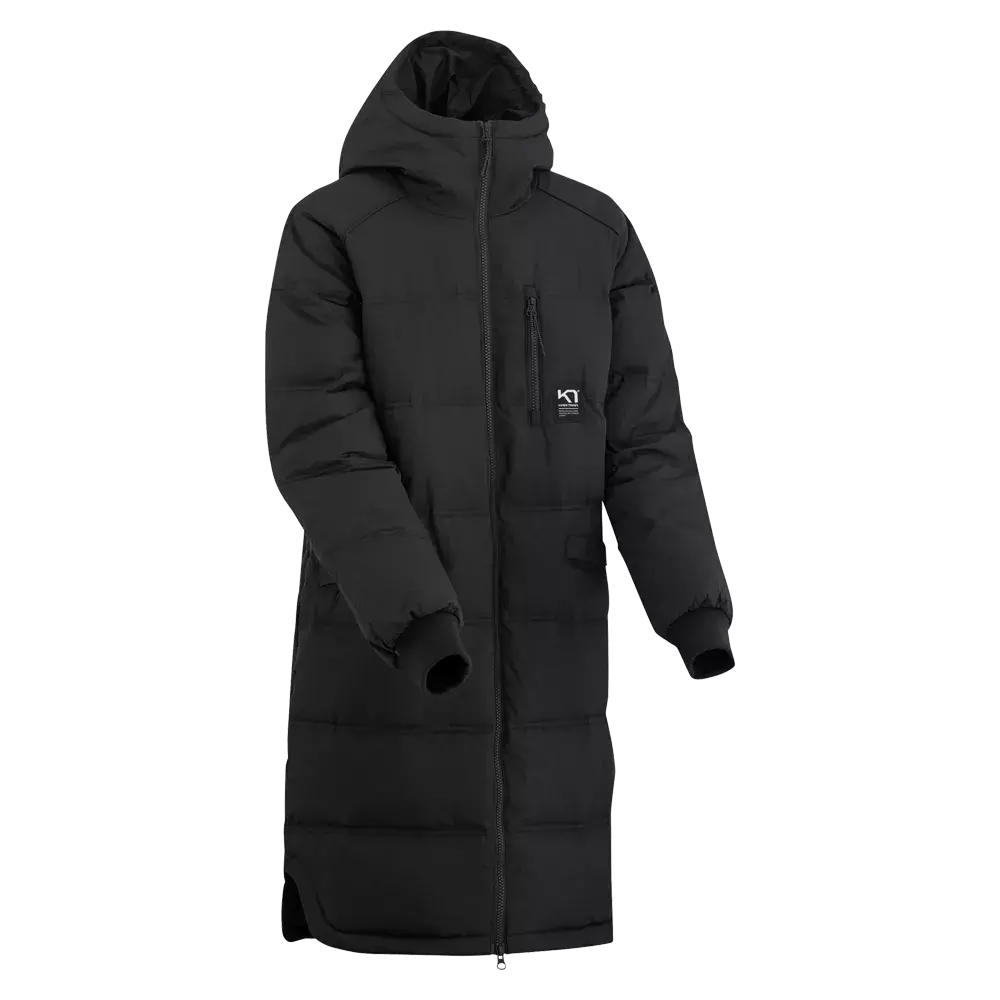En lang, sort, vatteret vinterfrakke med hætte og fuld længde lynlås. Jakken har kviltede sømme, ribbet indermanchet i ærmerne og en lille brystlomme med lynlås samt diskrete sidelommer. Det enkle, funktionelle design giver god isolering mod kulde og vind, samtidig med et minimalistisk og urbant udtryk, der fungerer til både hverdag og udendørs aktiviteter i koldt vejr.