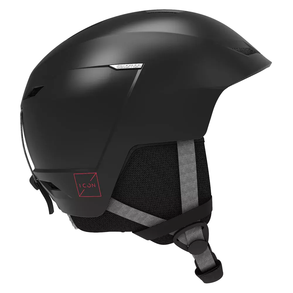 En elegant, mat sort hjelm designet til vintersport med aerodynamisk form og diskrete ventilationsåbninger. Polstret nakkestykke og bløde ørepuder giver komfort, mens justerbar hagerem sikrer sikker pasform. Hjelmen har en minimalistisk æstetik med subtile detaljer, herunder en lille rød ikon-mærkat og reflekterende stropper. Den virker robust og let, ideel til ski eller snowboard, hvor både beskyttelse og stil er vigtige.