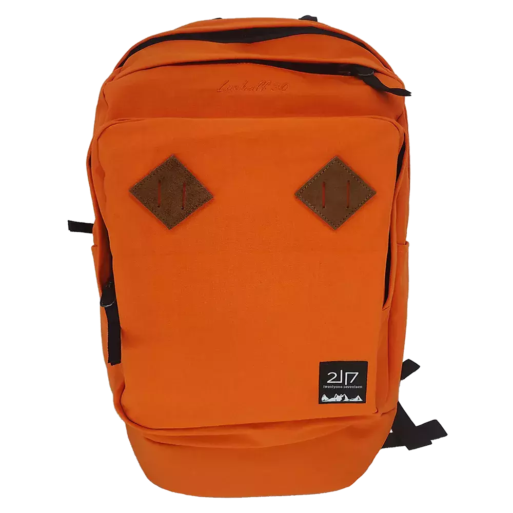 En klar orange rygsæk i robust lærredsstof med et enkelt, funktionelt design. Fronten har to brune diamantformede læderlapper, en lynlåslomme øverst og en rummelig hovedlomme. Sorte lynlåse og justerbare skulderstropper giver kontrast, mens et lille sort logoemblem nederst signalerer mærket. Rygsækken virker praktisk til skole, pendling eller dagsture med god opbevaringsplads og et tidløst, sporty udtryk.