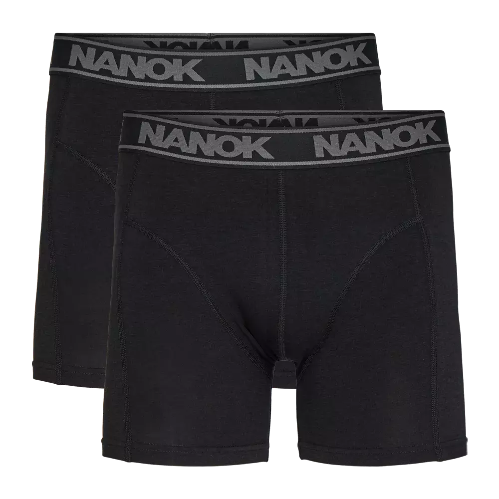 Billedet viser en dobbelpakke sorte boxershorts med længere ben og en bred elastiklinning prydet af det grå 'NANOK'-logo. Designet er enkelt og tidløst med flade syninger og formskærende paneler, der signalerer god støtte og komfort. Stoffet fremstår blødt og smidigt, velegnet til både hverdag og aktivitet. Et praktisk og stilrent valg til underdelen.