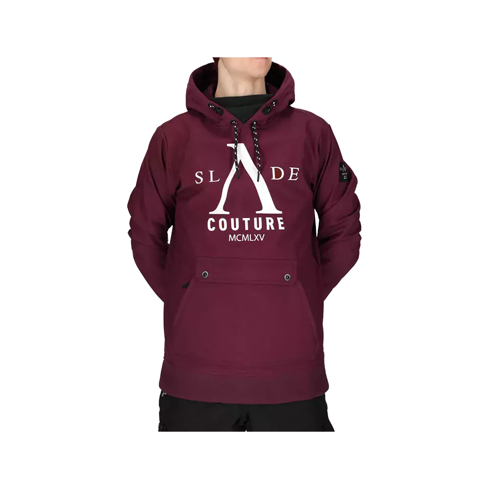 Billedet viser en mørkerød hættetrøje båret af en person med hovedet delvist uden for billedet. Trøjen har et markant hvidt bogstavslogo med teksten "COUTURE" og romertallet "MCMLXV" på brystet. Der er en frontlomme med trykknapper, sorte snore i hætten og et lille ærmemærke. Materialet ser tykt og varmt ud, velegnet til køligt vejr og casual brug.