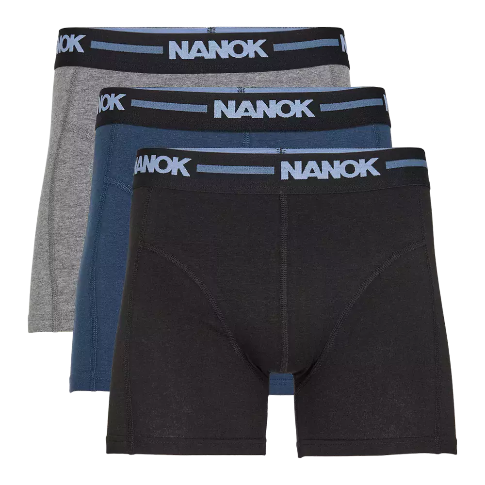 Et sæt tre boxershorts i klassisk, minimalistisk design: én sort, én blå og én grå. Hver har bredt, elastisk taljebånd i sort med lyseblåt "NANOK"-logo, flade syninger og en tætsiddende, støttegivende pasform. Materialet fremstår blødt og fleksibelt, ideelt til hverdag eller sport. Enkel farvepalet og diskret branding gør dem lette at matche med forskellige outfits.