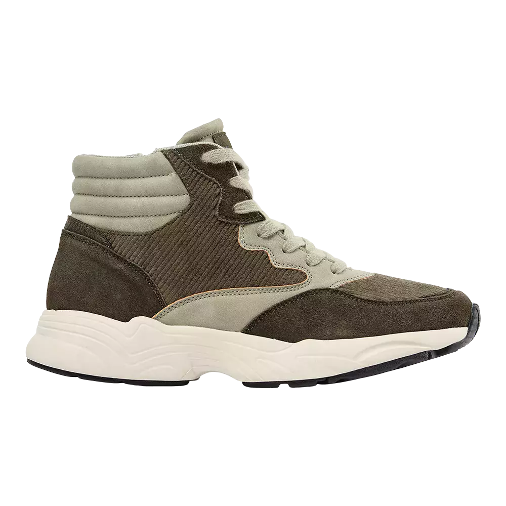 En høj sneaker i afdæmpede olivengrønne og khaki nuancer med en kombination af blødt ruskind og ribbet tekstil. Skoen har polstret ankelkrave, klassiske snørebånd og dekorative kontrastsømme. Den kraftige, bølget hvid mellemsål og sorte ydersål giver et sporty look og god stødabsorbering. Designet føles alsidigt og moderne, velegnet til hverdagsbrug i urbane og afslappede outfits.