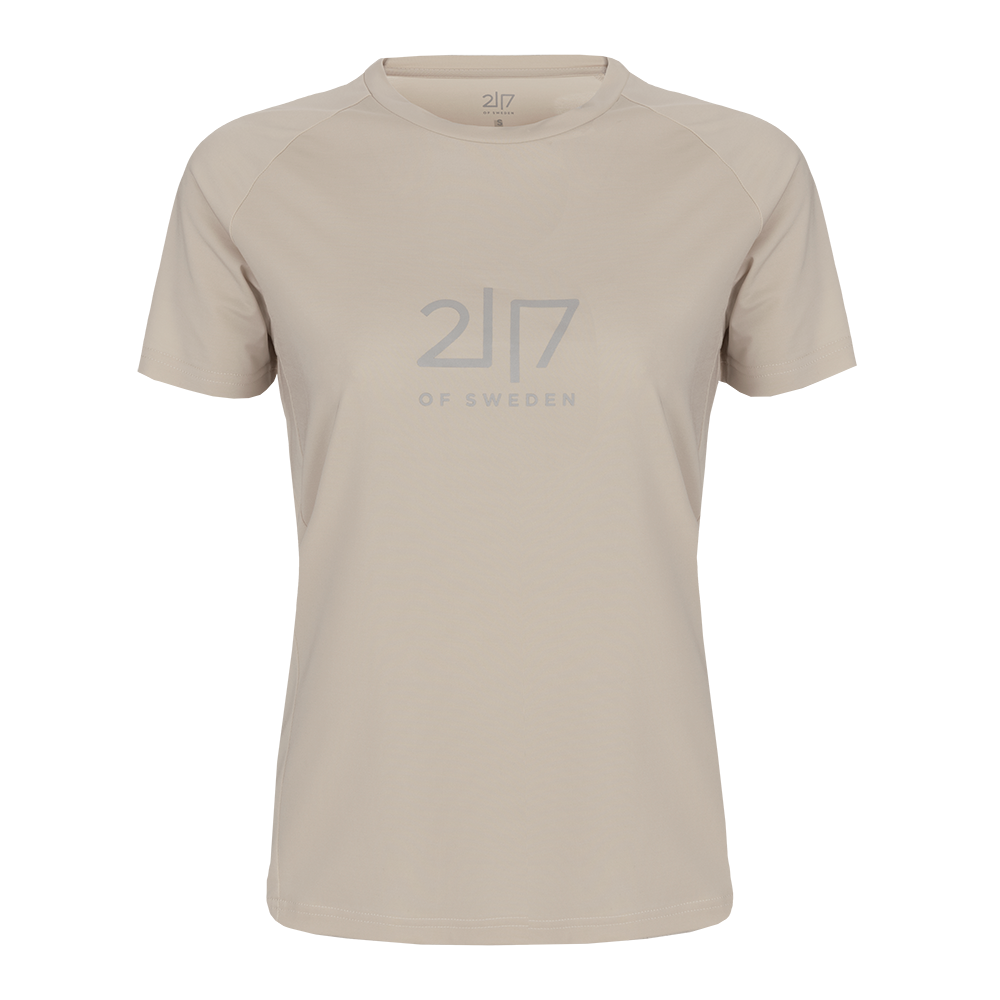 En enkel, sandfarvet T-shirt i blødt, let stof med rund hals og korte ærmer. Forsiden prydes af et diskret, gråt ’2|7 of Sweden’-logo, der giver et stilrent, minimalistisk udtryk. Skjorten har en afslappet pasform og rene syninger, velegnet til både hverdagsbrug og let træning. Den neutrale farve gør den nem at kombinere med jeans eller sportsbukser.