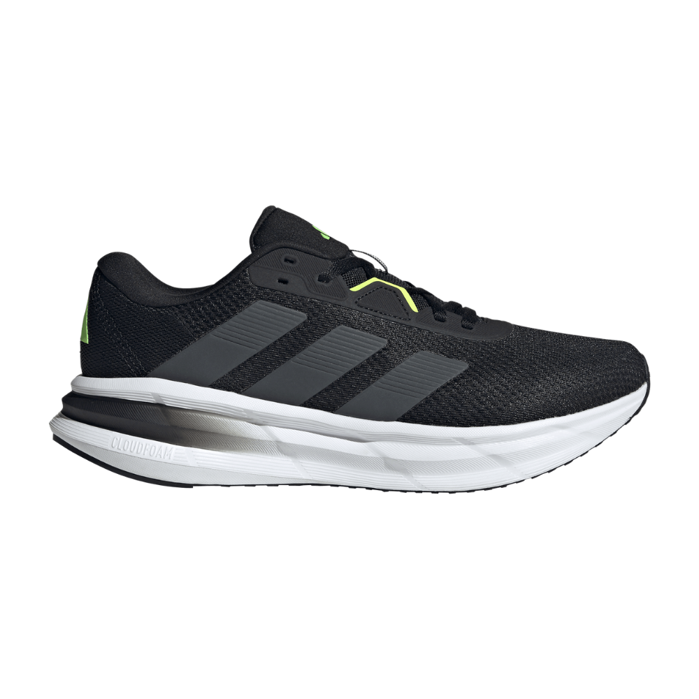 En moderne, sort løbesko med åndbart mesh og tre tonede striber langs siden, tydeligt inspireret af Adidas-design. Den hvide, tykke mellemsål med Cloudfoam-dæmpning giver et luftigt og responsivt afsæt, mens små neongrønne detaljer tilfører et sportigt touch. Skoens lave hælkrave og snørebånd sikrer stabil pasform, egnet til både træning og hverdag med et stilrent, dynamisk udtryk.