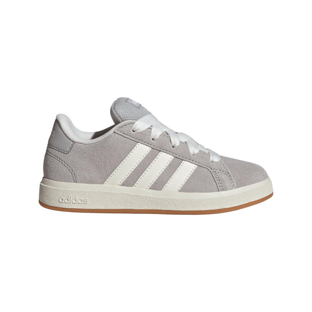 En lav snøresneaker i lysegråt ruskind med tre hvide striber langs siden. Skoen har hvide snørebånd, polstret krave og en cremefarvet mellemsål med 'adidas'-tryk, samt en gumfarvet ydersål. Det enkle, retro-inspirerede design gør den velegnet til hverdagsbrug og afslappet stil, med fokus på komfort og diskret æstetik og holdbarhed i materialerne.