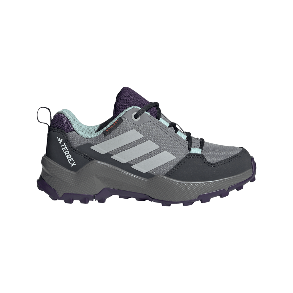 Et robust vandre-/trailsko i grå nuancer med tre lyse striber på siden og "TERREX" trykt på hælen. Skoen har en kraftig, mønstret sål med dybe dupper for godt greb, forstærket tåparti, polstret krave og snørebånd for sikker pasform. Indvendig ses mintgrøn foring og mørkelilla detaljer ved tunge og sål, hvilket giver både funktionalitet og et sporty udtryk.