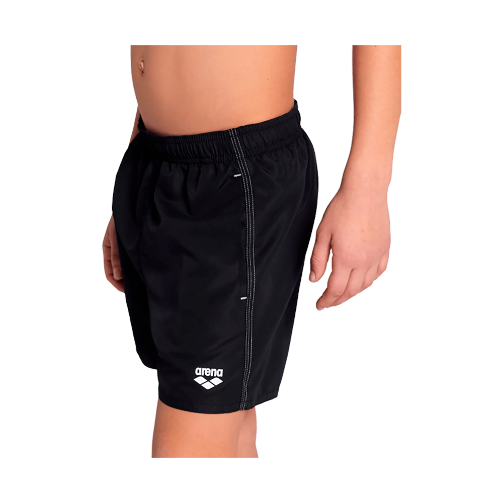 Billedet viser en ung person iført sorte badeshorts fra Arena. Shortsene har elastisk talje, knælængde pasform og et lille hvidt logo nederst på venstre ben. Siderne har synlige kontrastsømme og en enkel, sporty silhuet. Materialet virker let og hurtigtørrende, velegnet til svømning eller strandbrug. Farven er klassisk sort, hvilket giver et tidløst og neutralt udtryk.