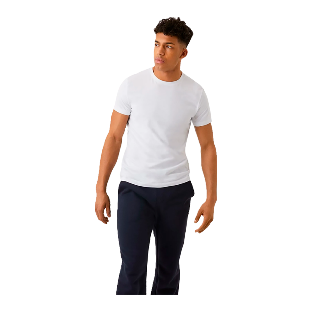 En ung mand står afslappet i en enkel, hvid t-shirt og mørke bukser. Han har kort, krøllet hår og en neutral, eftertænksom mine, mens han kigger let til højre. Armene hænger løst ned langs siden, og kropsholdningen virker rolig og selvsikker. Billedet fremhæver et minimalistisk, moderne udtryk med fokus på tøjvalg og naturlig fremtoning.