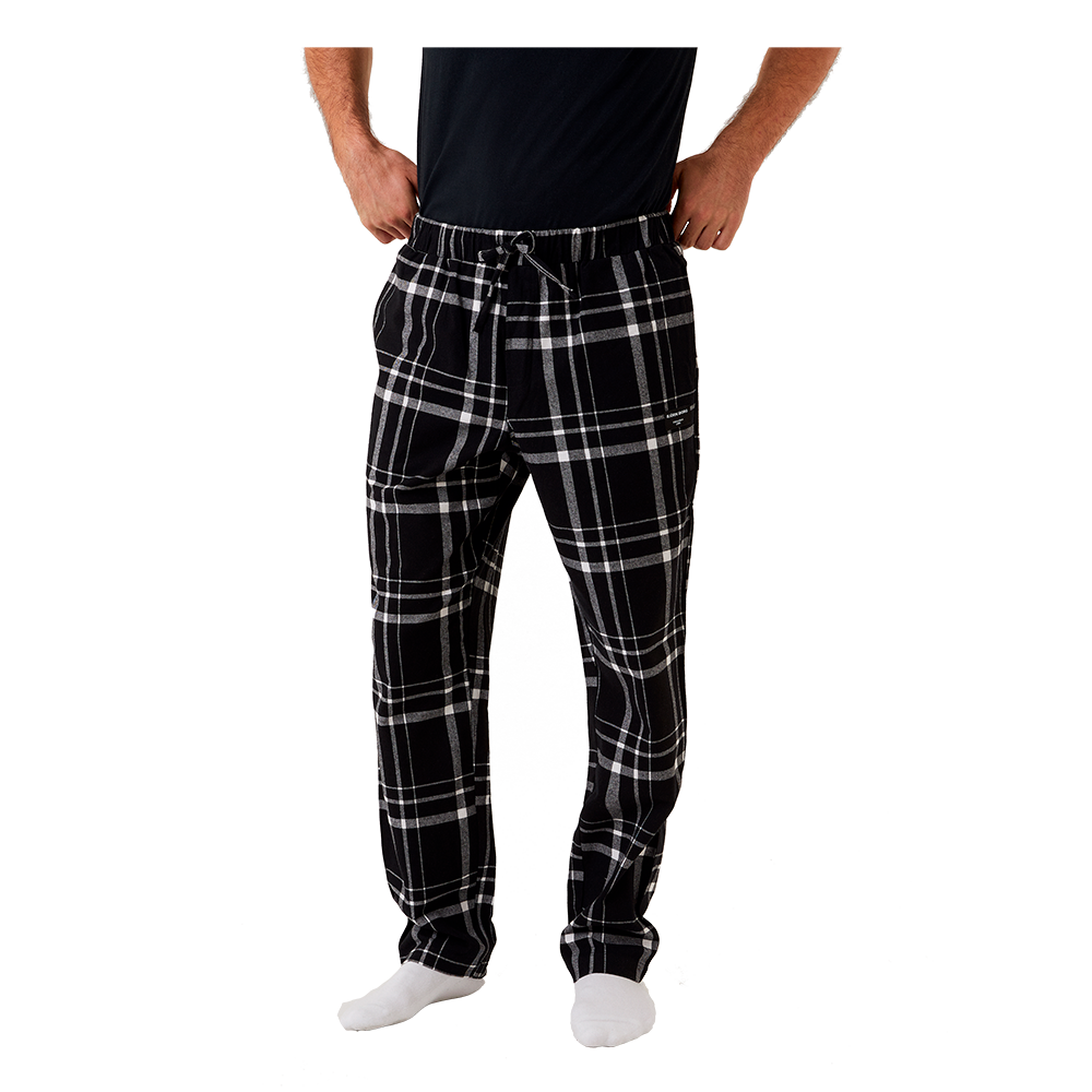 Billedet viser en person iført sorte pyjamasbukser med et stort ternmønster i hvidt og gråt. Bukserne har elastik i taljen med snøre, sidelommer og et afslappet, lige snit, der giver et behageligt udtryk. Stoffet fremstår blødt og varmende, velegnet til hygge derhjemme eller til natbrug. Personen står i hvide sokker og en sort overdel er kun delvist synlig.