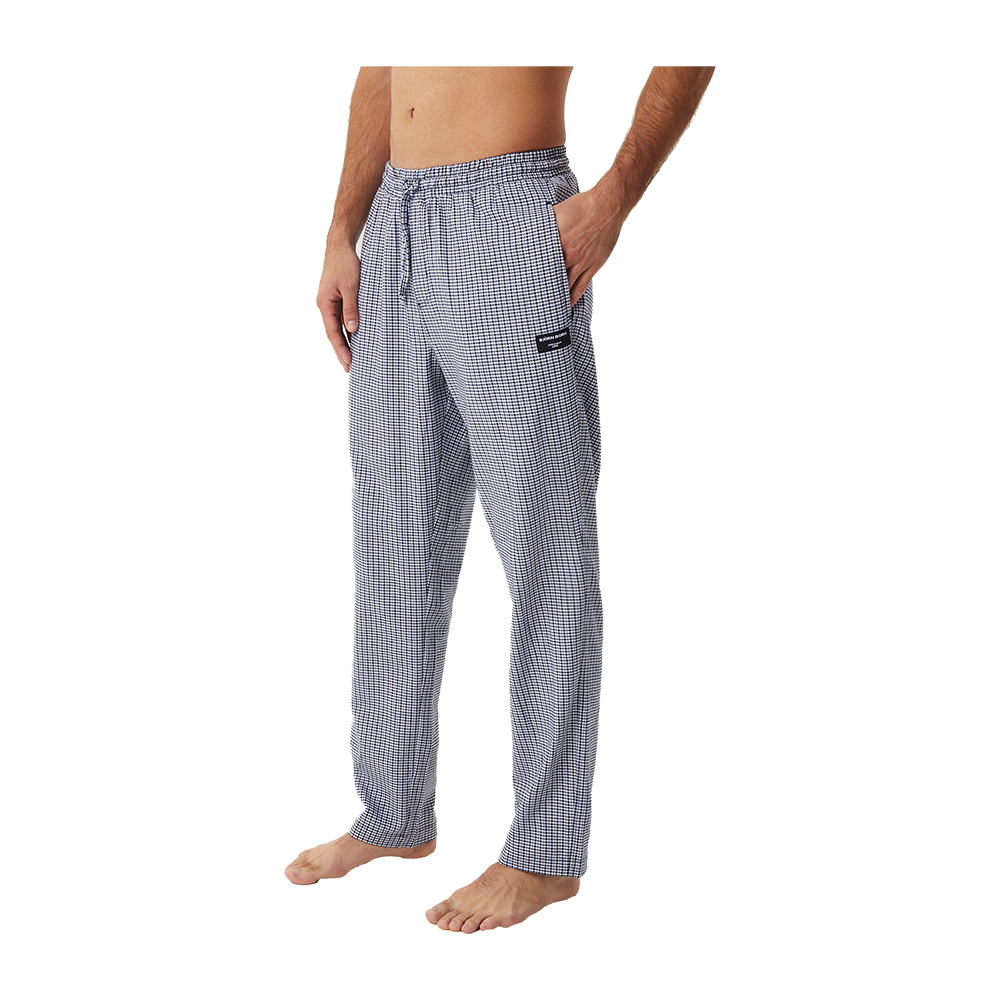 etiket på låret. Stoffet virker blødt og løstsiddende, velegnet til afslappet hjemmebrug eller søvn. Modellen står barfodet, hvilket fremhæver buksernes komfortable og afslappede udtryk. Mønstret er diskret og tidløst, så bukserne passer til mange stilarter.