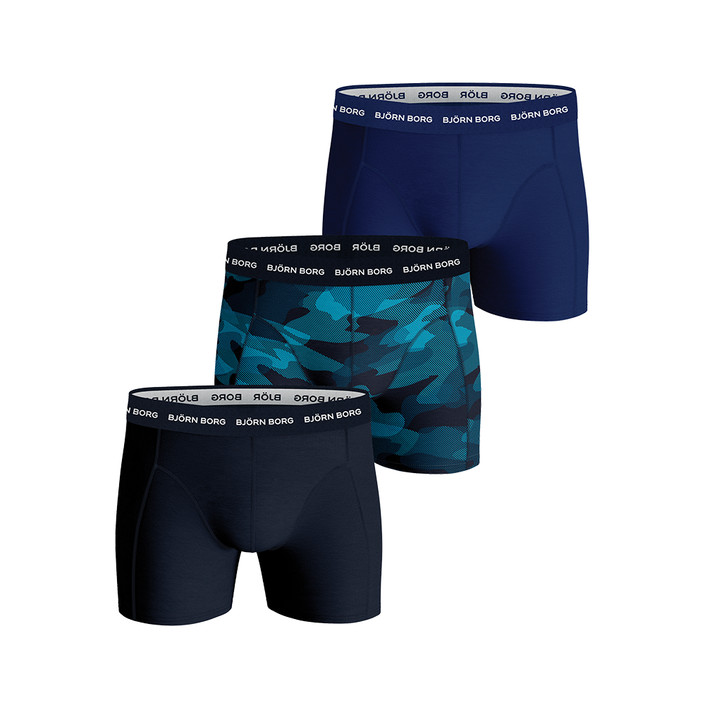På billedet ses et sæt af tre Björn Borg boxer shorts i blå toner. Modellerne har tætsiddende pasform, flade syninger og bred elastisk linning med gentagne "BJÖRN BORG"-logo. Designet inkluderer en ensfarvet mørkeblå, en solid marine og en moderne blå camouflagevariant. Materialet fremstår blødt og åndbart, velegnet til hverdag og sport med fokus på komfort og bevægelsesfrihed.