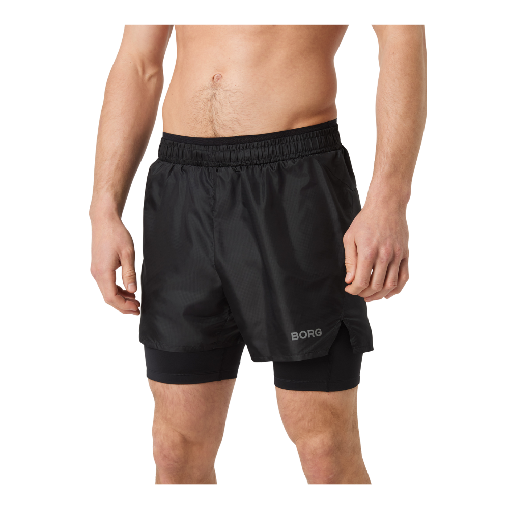 Et billede af en mandlig torso iført sorte løbeshorts med indbygget compression-tights under. Shortsen har elastisk talje og kort sidesprække, hvor mærket "BORG" ses diskret på venstre ben. Armene hænger afslappet ned langs siden, og hud og ben er tydeligt synlige fra talje til knæ. Materialet virker let og glat, egnet til træning eller løb.