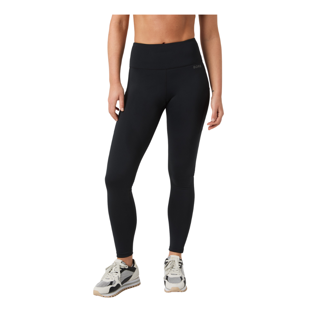 Denne billedfremstilling viser en model iført sorte, højttaljede træningsleggings med tætsiddende pasform og glat overflade. Bukserne fremhæver taljen og følger benets form, samtidig med de giver et diskret sporty look med lille 'BORG'-logo ved hoften. Stylingen kompletteres af hvide og grå løbesko. Leggingsene virker velegnede til både træning og hverdagsbrug på grund af deres enkle, funktionelle design.