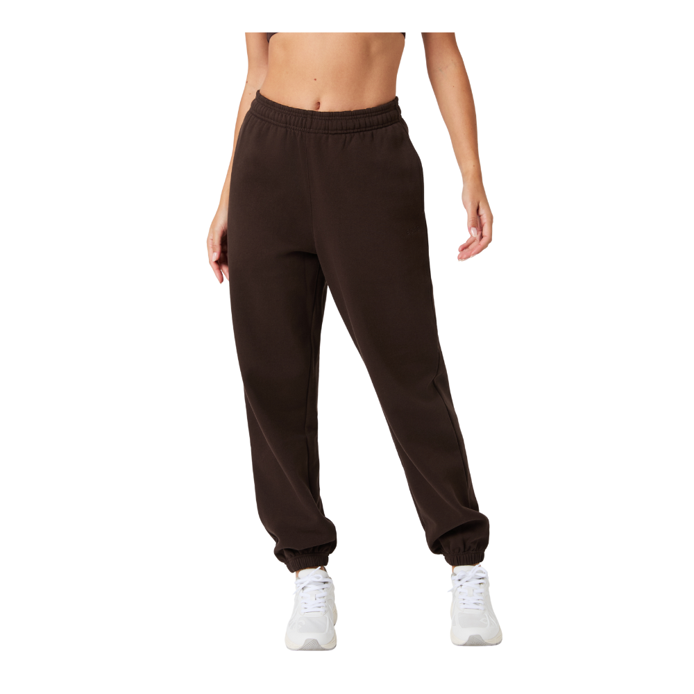 Et par mørkebrune jogger-bukser i blødt, kraftigt stof med elastisk talje og manchetter ved anklerne. Modellen har en afslappet, let poset pasform, der falder glat langs benene, og bukserne harmonerer med hvide sneakers for et sporty, hverdagsagtigt look. Designet virker praktisk og komfortabelt til afslapning eller let træning, og den neutrale farve gør dem nemme at style.