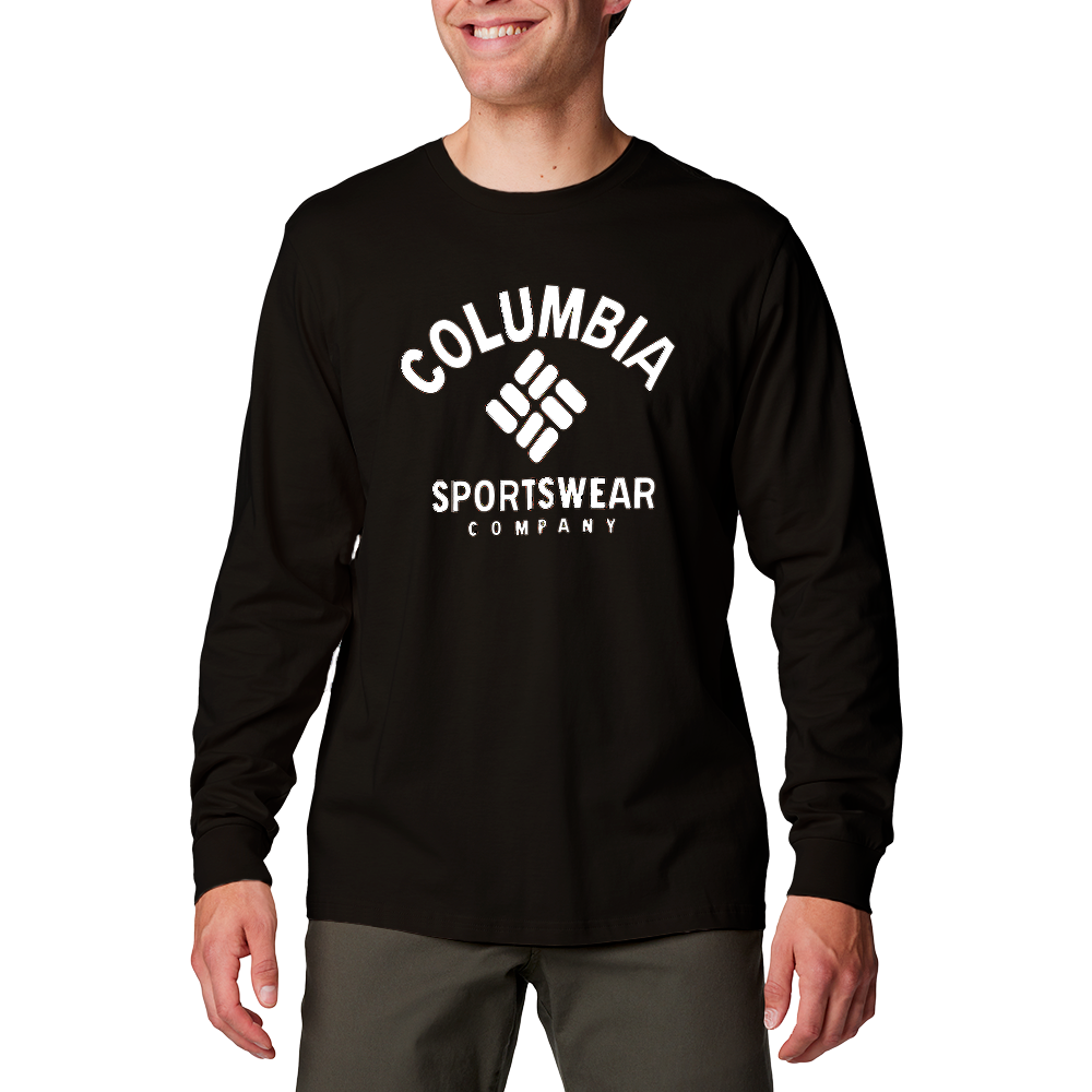 En person står afslappet iført en sort, langærmet t-shirt med et tydeligt hvidt Columbia Sportswear Company-logo midt på brystet. Modellen smiler let og har hænderne afslappet ned langs siderne. T-shirten er enkel og sporty, kombineret med mørke bukser. Billedet fremhæver trykket og pasformen på overdelen, hvilket giver et casual og funktionelt indtryk velegnet til fritid eller udendørs aktiviteter.