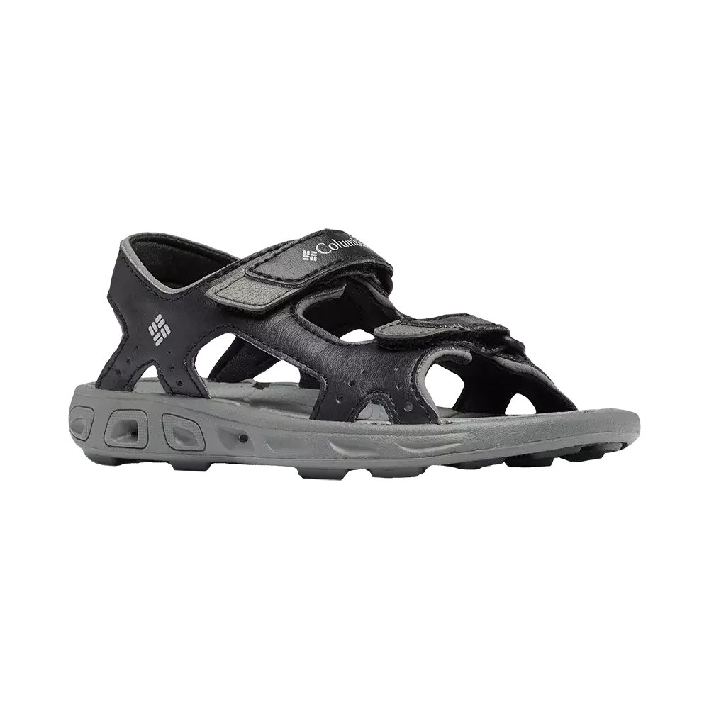 Sort og grå sportsandal fra Columbia med åbne sider og justerbare velcroremme foran og ved anklen. Den har en robust, profileret sål i gråt skum med gode drænhuller og greb, samt perforerede detaljer i overdelen for ventilation. Designet kombinerer komfort og funktionalitet til udendørs brug, vandaktiviteter og længere gåture, og fremstår som et praktisk valg til aktiv fritid.