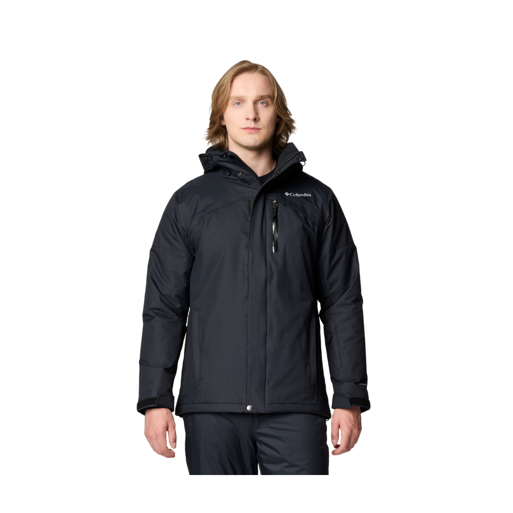 En person står lige frem og bærer en mørk, sort Columbia-vinterjakke med hætte. Jakken har en vandtæt glidelåslomme på brystet, justerbare manchetter og en lige pasform, der beskytter mod kulde. Personen har skulderlangt lyst hår, neutral mine og afslappet kropssprog. Baggrunden er neutral, så fokus er på jakken og dens funktionelle detaljer.
