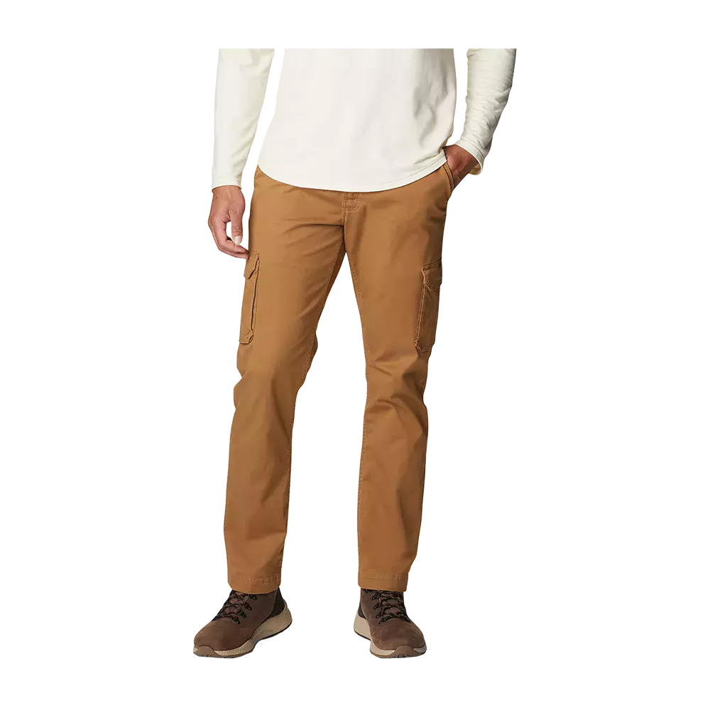 Billedet viser en person iført et par karrybrune cargobukser i et robust bomulds- eller canvaslignende materiale. Bukserne har sidelommer med klap, et lige snit og sidder afslappet omkring anklerne. Overdelen er en lys, langærmet trøje, og fødderne er i brune vandrestøvler. Samlet giver looket et praktisk, udendørs- og hverdagsorienteret udtryk, velegnet til arbejde og fritid.