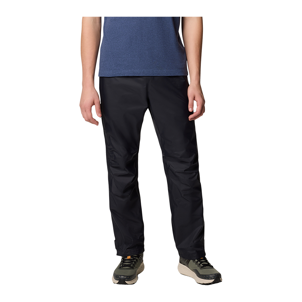 Et par sorte, lige skårne overtræksbukser i let, vandafvisende materiale ses sammen med en blå t‑shirt og grågrønne vandresko. Bukserne har en afslappet pasform, lige ben og ser praktiske og komfortable ud til udendørs aktiviteter i vådt vejr. Det enkle, funktionelle design gør dem velegnede til vandreture, rejser eller daglig brug, hvor bevægelsesfrihed og beskyttelse mod regn er vigtig.