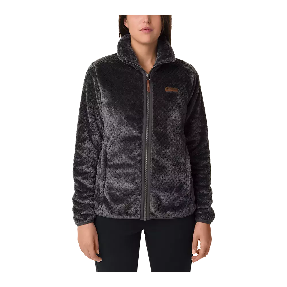 En blød, mørkegrå fleecejakke med fuld lynlås og høj krave ses på billedet. Jakken har en let tekstureret, pelsagtig overflade, lange ærmer og diskrete sidelommer. Pasformen er afslappet og varmeisolerende, velegnet til kølige dage. Det enkle, minimalistiske design kombinerer komfort og funktionalitet, hvilket giver et casual og hyggeligt udtryk. Farven er neutral og nem at style.