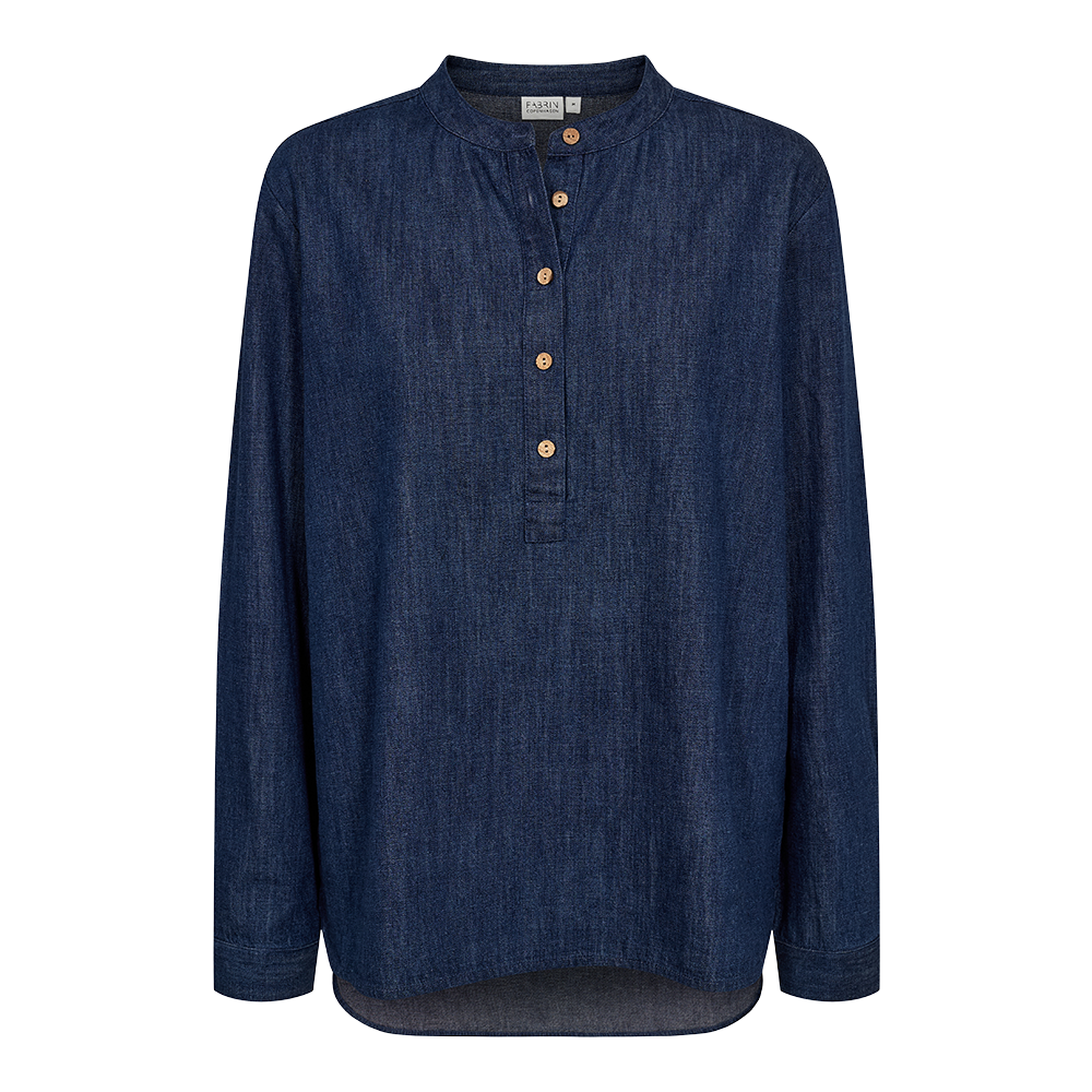 Mørkeblå denimbluse med rund hals og kort knappelukning, fire lyse træknapper langs brystet. Langærmet, let oversize snit med blød, struktureret denimkvalitet og diskret afrundet kant forneden. Enkel, tidløs og afslappet stil, velegnet til både hverdag og lag på lag-look. En neutral, sart men robust bluse, som kan styles med jeans, chinos eller nederdel for et afslappet, elegant udtryk.