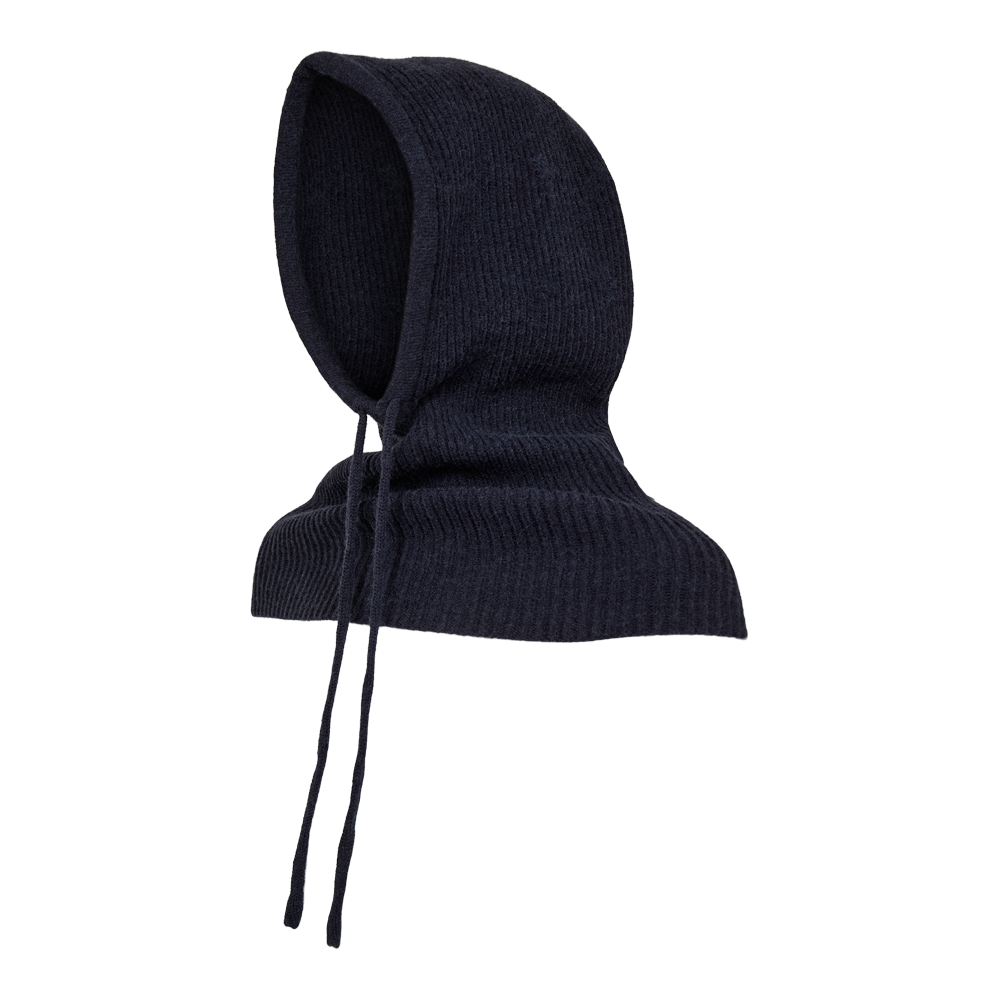 Billedet viser en mørkeblå, ribstrikket hætte der dækker hoved og skuldre på en hvid mannequin. Hætten har en dyb, afrundet form med lange snore, der hænger ned foran. Materialet ser blødt og varmt ud, egnet til koldt vejr eller som et stilrent accessories. Farven er ensartet og giver et minimalistisk, nordisk udtryk. Designet kombinerer funktionalitet og æstetik.