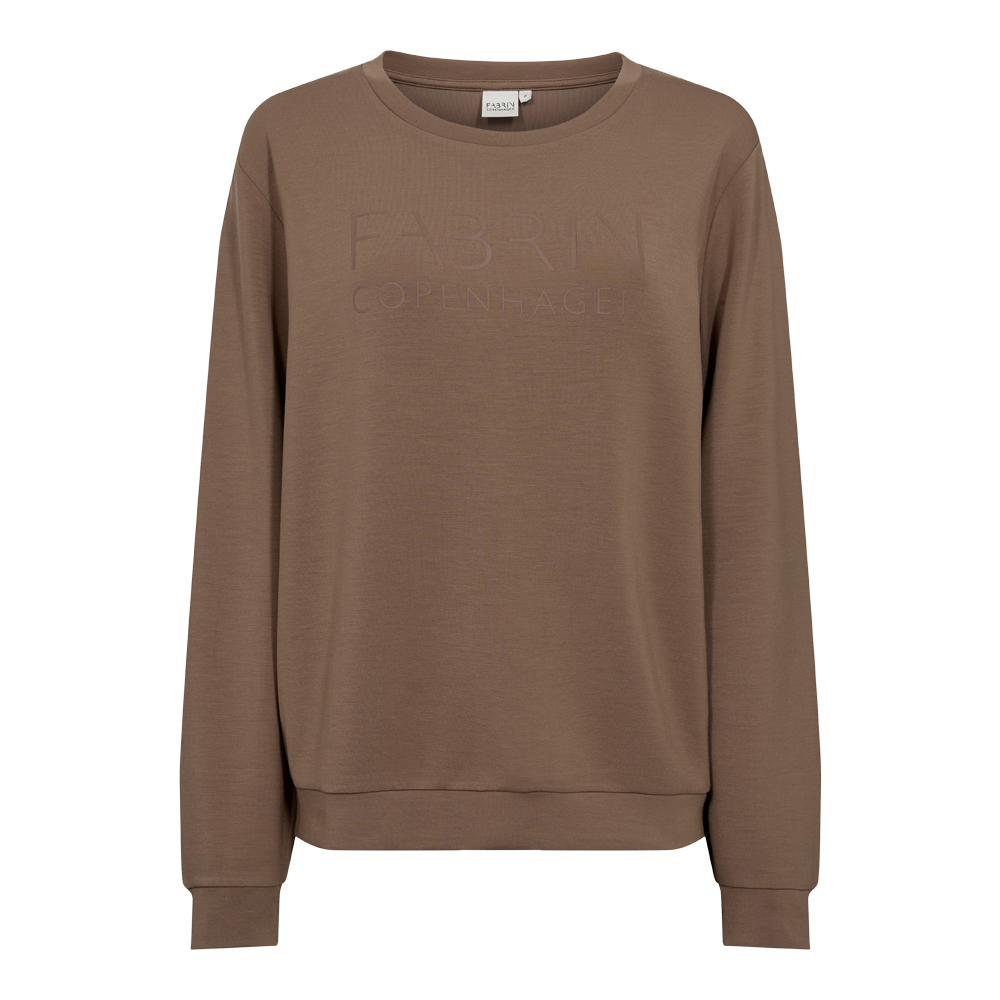 En enkel, jordfarvet sweatshirt i varm brun nuance med rund hals og lange ærmer. Designet er minimalistisk med diskret, ton-i-ton logopræg på brystet og ribkanter ved ærmer og talje. Materialet virker blødt og let struktureret, hvilket giver et afslappet men elegant udtryk. Perfekt til hverdagsbrug, brug som lag over en skjorte eller kombiner med jeans for et casual, skandinavisk look.
