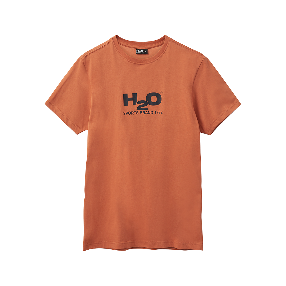 En simpel, kortærmet T‑shirt i en varm orange nuance med rund halsudskæring og et sort brysttryk: "H2O" med teksten "Sports Brand 1982" under. Designet er minimalistisk og sporty, med rene syninger og et ubesværet, afslappet snit. Ideel til hverdagsbrug eller let træning, og nem at kombinere med jeans, shorts eller lag-på-lag outfits.