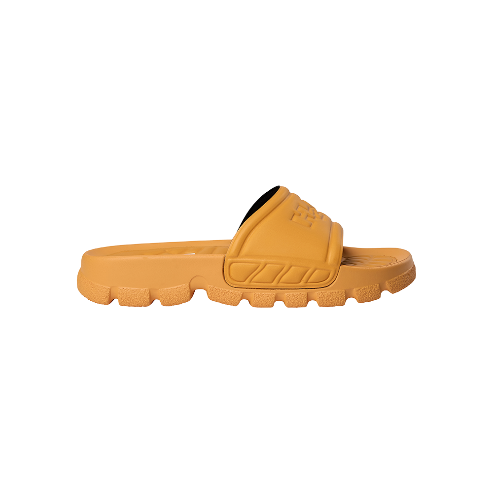 En moderne, robust guld-orange slide-sandal med en bred, polstret rem over vristen og en tyk, rillede sål. Sandalen har en formstøbt fodseng for komfort og et kraftigt mønster under sålen for godt greb. Materialet virker som blød EVA eller gummi, hvilket gør den let, vandafvisende og ideel til afslappet brug ved stranden, hjemme eller i byen.