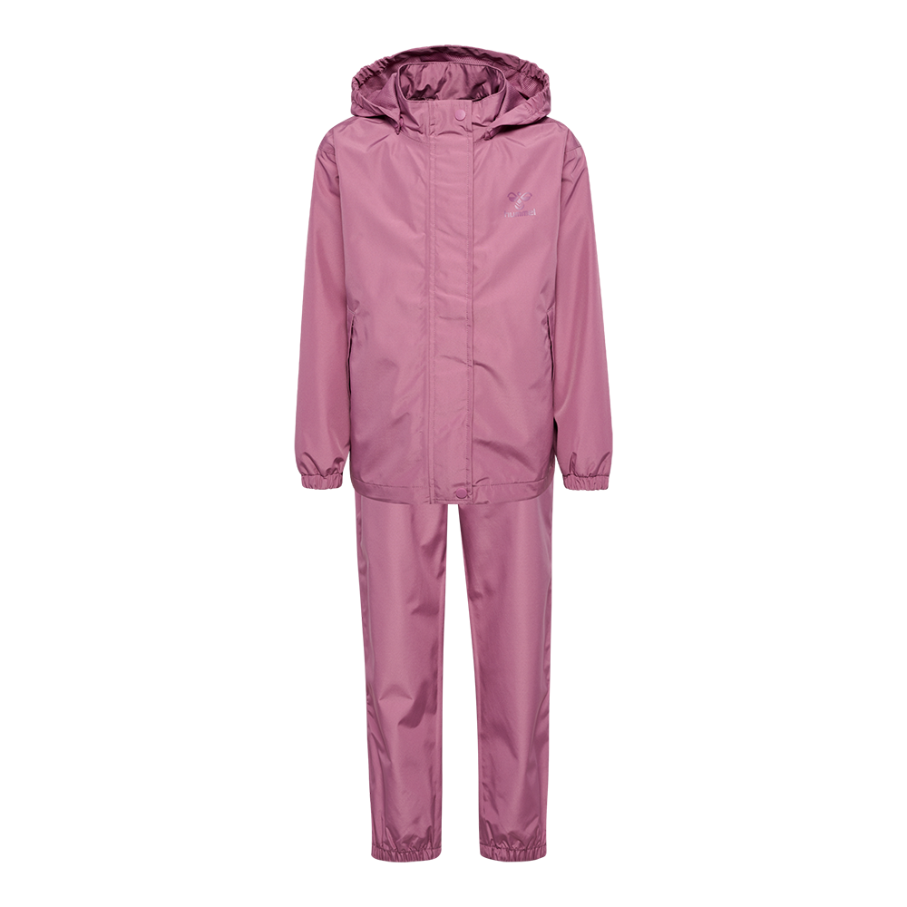 En stilren, støvet lyserød regnjakke og bukser i ensfarvet design. Sættet har hætte, lynlås med overliggende stormklap og elastiske ærme- og benafslutninger, der holder regn ude. Materialet virker vandafvisende og slidstærkt, og et diskret logo pryder brystet. Praktisk og funktionelt sæt til vådt vejr, velegnet til udendørs leg eller hverdag, hvor beskyttelse og bevægelsesfrihed er vigtig.