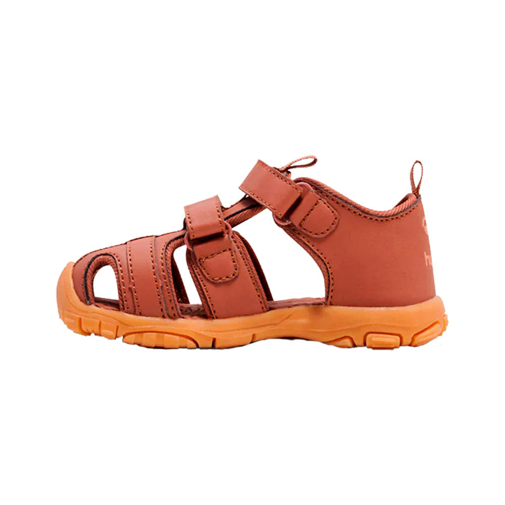 Brun-orange børnesandal med lukket hæl og åbent forreste design, lavet i blødt syntetisk læder og med robust orange gummisål. To velcroremme over vristen gør sandalen nem at justere og tage af og på, mens forstærkede syninger øger holdbarheden. Åbningerne langs siderne sikrer god ventilation, og den profilerede sål giver skridsikring til leg og udendørsaktiviteter om sommeren.