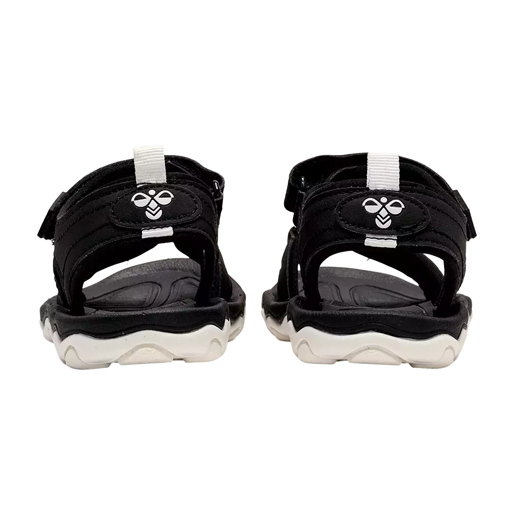 På billedet ses et par sorte sportssandaler set bagfra. De har brede justerbare velcrostropper, polstret hælkappe og en hvid, profileret gummisål. Indlægssålen virker formstøbt for komfort, mens den robuste sålekonstruktion giver greb og stabilitet. Sandalerne har et simpelt, funktionelt design med kontrastdetaljer og er velegnede til hverdag, fritid og let udendørsbrug om sommeren.