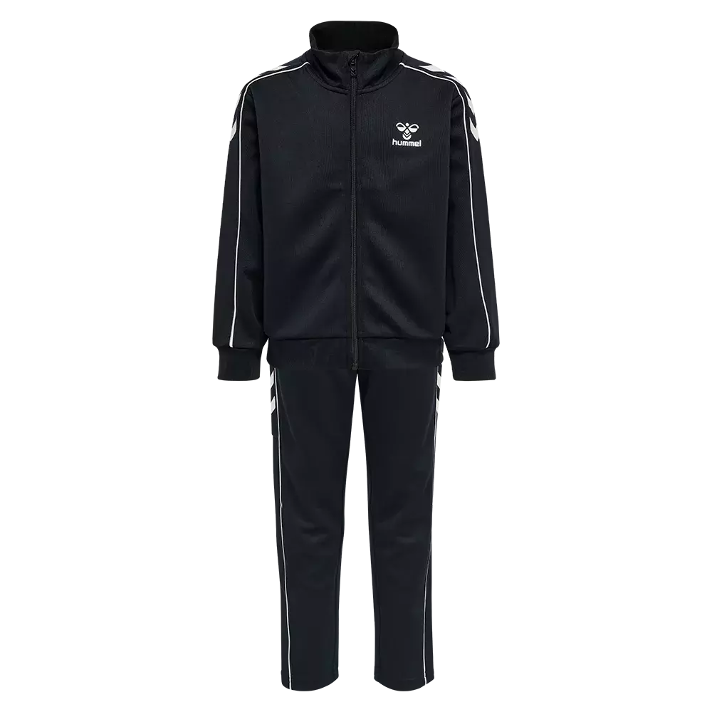 Sort træningssæt bestående af en fuld-lynlås jakke og matchende bukser. Jakken har høj krave, ribmanchetter og hvide kontraststriber langs ærmerne, mens bukserne er tætsiddende med hvide sidekanter. Hummel-logoet og karakteristiske chevrons pryder brystet og skuldrene. Sættet er i sportigt, let materiale og giver et enkelt, moderne look, velegnet til både træning og afslappet hverdag. Farverne er klassiske og nemme at kombinere med andre ting.