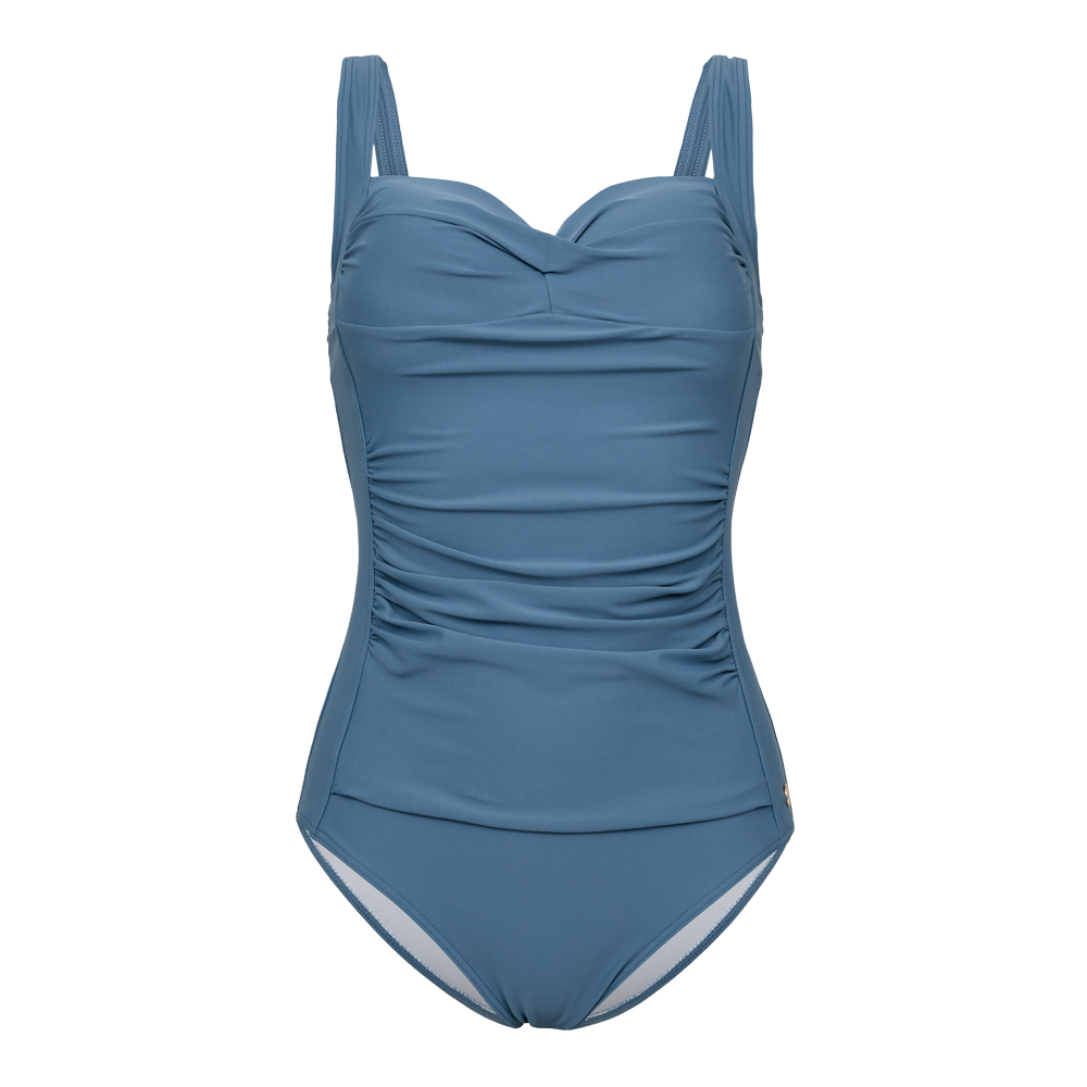 Denne elegante badedragt i støvet blå har en klassisk, feminin silhuet med hjerteformet bærestykke og brede stropper for god støtte. Let rynkede detaljer langs maven skaber et formende og flatterende udtryk, mens glatte sømme og enkel linjeføring giver et tidløst look. Ideel til både pool og strand, kombineres den nemt med en sarong eller let kimono for en sofistikeret sommerstil.