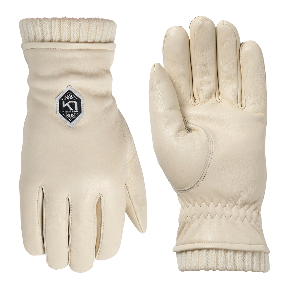 Et par cremefarvede læderhandsker med blød, glat overflade og ribstrikket manchet. Handskerne har diskrete syninger, forstærket tommelfinger og et lille, geometrisk logo på oversiden. Designet kombinerer minimalistisk æstetik og praktiske detaljer og egner sig godt til koldt vejr eller som stilfuldt tilbehør. Den lyse farve og det rene snit giver et elegant, nordisk udtryk.