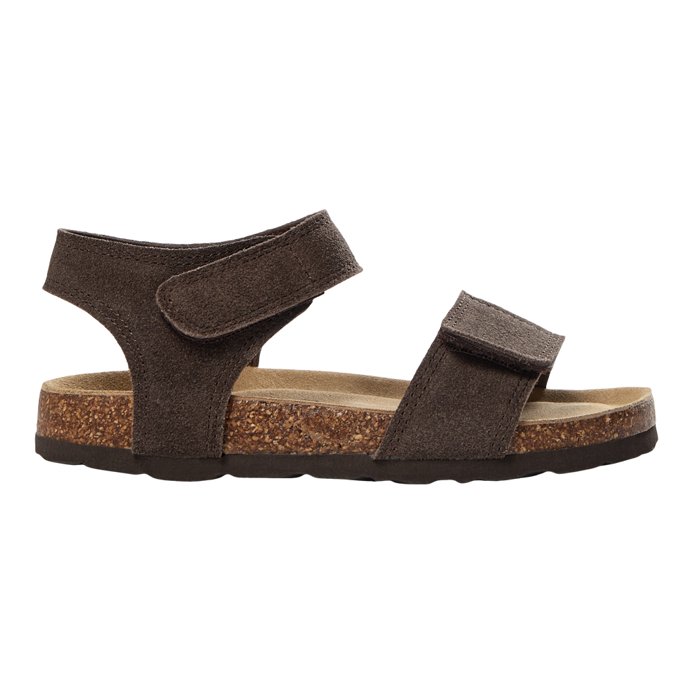 Brun sandal i ruskind med to brede velcro-remme over forfoden og om anklen. Indersålen er formstøbt med blødt, lysebrunt indlæg, og mellemsålen er lavet af kork med synlig tekstur, mens ydersålen er mørk gummi. Designet er enkelt og funktionelt, egnet til afslappet hverdag og varme dage, hvor komfort og justerbar pasform prioriteres.