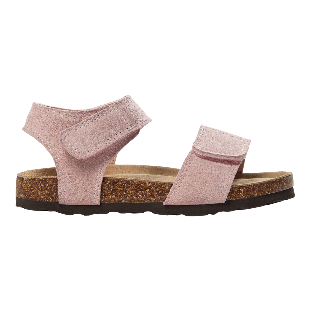 En enkel rosa sandal i blødt ruskind med to brede velcrolukninger — en over forfoden og en ved anklen — hviler på en formbar korksål med en mørk gummiydersål. Indersålen ser anatomisk ud og lover god støtte og komfort til hverdagsbrug. Sandalens enkle, afslappede design gør den velegnet til sommerbrug og kombinerer funktionalitet med et blødt, feminint udtryk.