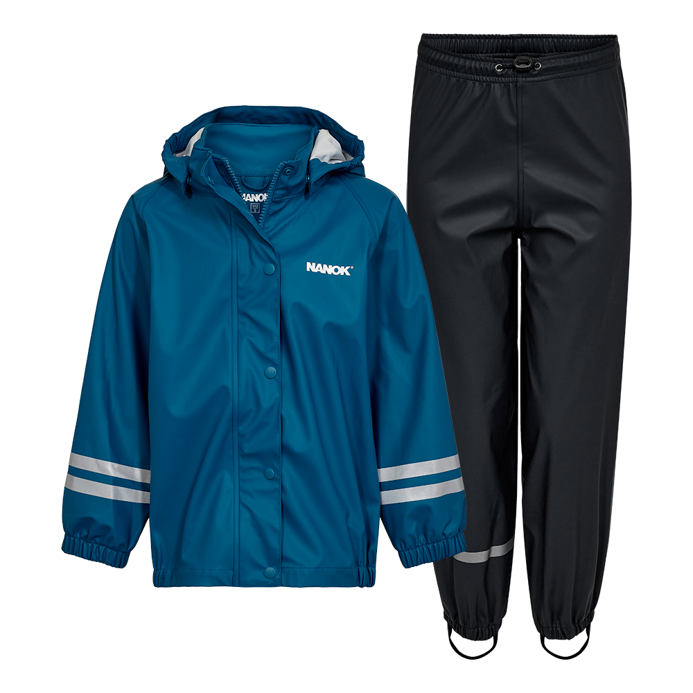 Et praktisk regnsæt bestående af en petrolblå jakke og sorte overtræksbukser. Jakken har hætte, trykknapper, elastiske ærmegab og reflekser på ærmerne samt logo på brystet. Bukserne har elastisk talje med snørre, reflekterende bånd ved anklerne og stropper under fødderne for at holde buksebenene på plads. Sættet virker holdbart, vandtæt og velegnet til børn i vådt vejr.