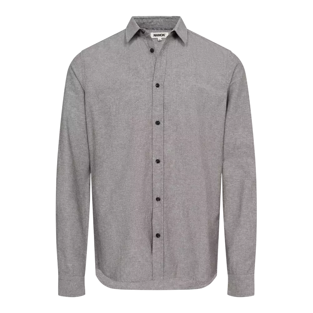 En enkel, grå langærmet skjorte med klassisk krave og fuld knaplukning. Stoffet har en diskret, fin struktur, og kontrasterende sorte knapper giver et stilrent udtryk. Skjorten fremstår afslappet i pasformen og fungerer både til hverdag og mere formelle lejligheder. Det tidløse design gør den nem at kombinere med jeans eller chinos for et enkelt, velklædt look.