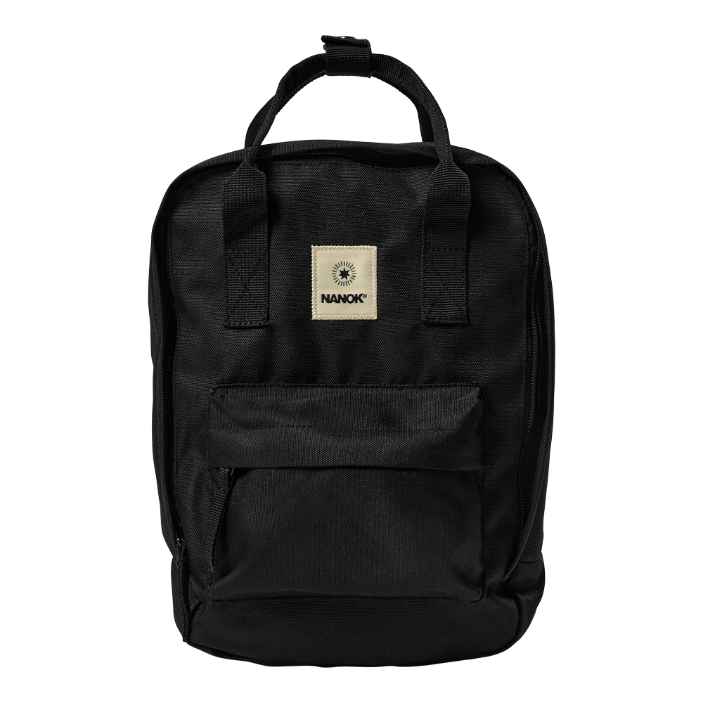 Sort, kompakt rygsæk i robust, vævet stof med et enkelt og funktionelt design. Den rektangulære form har et stort hovedrum med lynlås, en frontlomme med klap og forstærkede bærehåndtag i toppen. Et beige logo-patch med teksten "NANOK" bryder det mørke udtryk. Rygsækken virker praktisk til hverdag, studie eller korte ture og udstråler holdbarhed og minimalistisk stil.