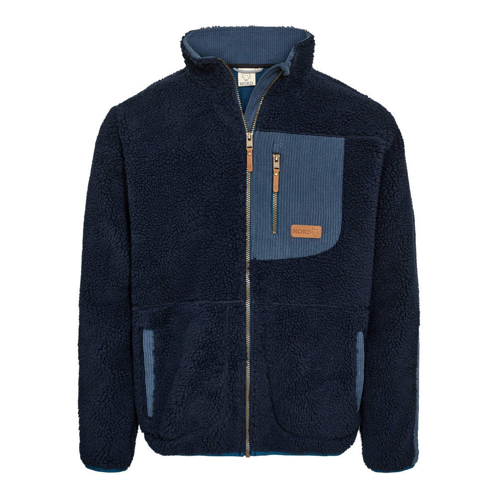 En mørkeblå fleecejakke i teddy-stof med fuld lynlås og opretstående krave. Jakken har kontrastdetaljer i lysere blå ribbet kordfløjl på brystlomme og lommekanter samt en lille læderlogo-patch. To forlommer og en lynlåslukket brystlomme giver praktisk opbevaring. Designet virker varmt, blødt og afslappet — velegnet til kølige dage og uformelle udendørsaktiviteter. Perfekt som mellemlag under en jakke eller alene på milde vinterdage.