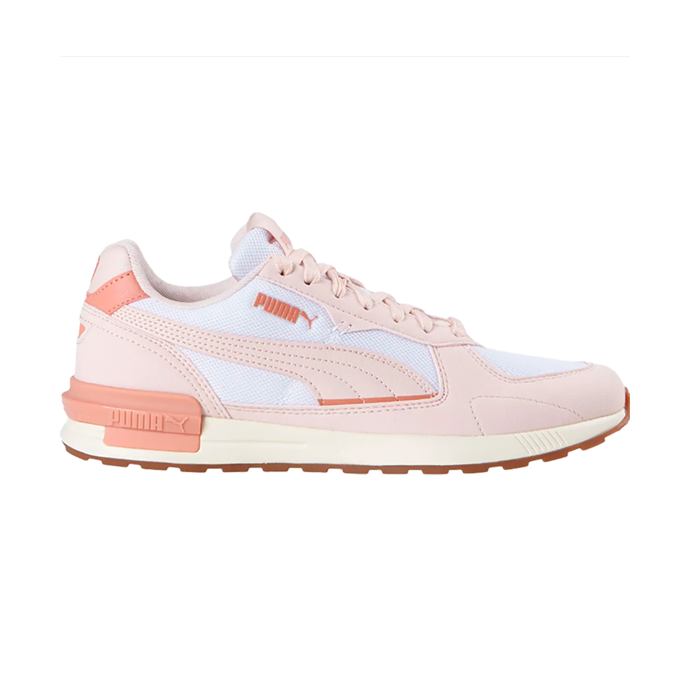 En elegant lyserød Puma-sneaker i profil, kombinerer blødt pastelrosa læder og hvidt mesh med koralfarvede detaljer. Sneakersen har klassisk Puma-form med den ikoniske stribe og diskret logo ved siden og på hælen. Sålens kontrastfarvede gummiyderside og affjedrende mellemsål giver et sporty, retro-inspireret look, velegnet til både hverdag og let træning.