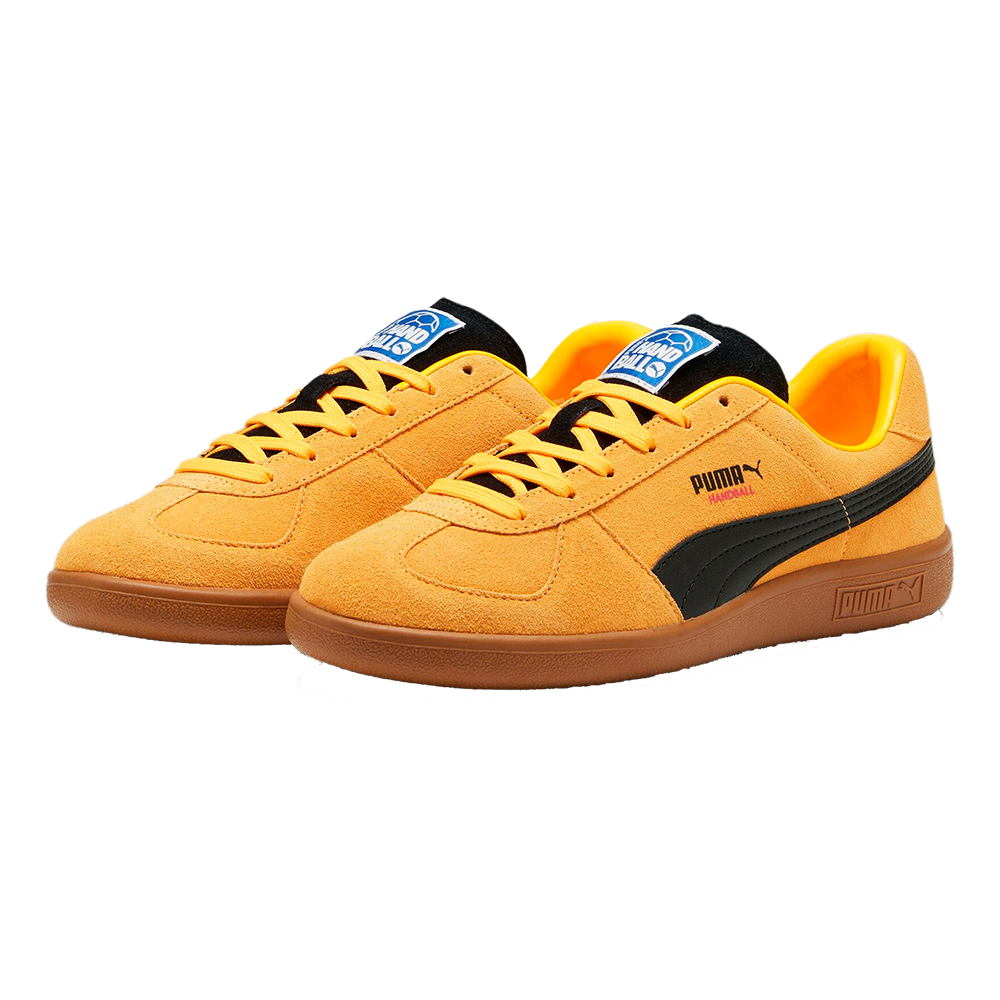 Et par PUMA-sneakers i varm orange ruskind med sorte detaljer og brun gummisål. Skoene har kontrastfyldte såler, matchende orange snørebånd og en sort PUMA-stribe langs siderne. Indersålen er lyseorange, og logoer på tunge og yderside giver et sporty retro-udtryk. Designet er enkelt og stilrent, velegnet til hverdag eller casual streetwear.