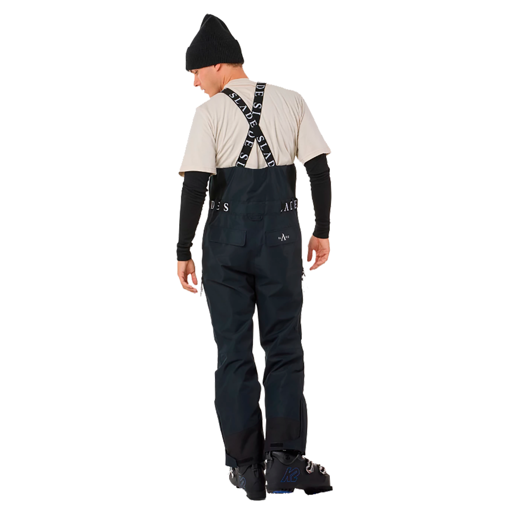 Den unge mand på billedet er klædt i "Slade Aspen Bib Pants" skibukser fra Slade, designet til mænd. Disse bukser har en mørk navy farve og er udstyret med robuste seler, der fremhæver det sporty look. Han bærer også en sort strikhue, hvilket tilføjer en afslappet stil til det funktionelle skitøj. Buksernes mange lommer og holdbare materiale gør dem ideelle til vinteraktiviteter på ski. Skibukserne ser ikke blot smarte ud, men er også praktiske og komfortable for enhver skientusiast.