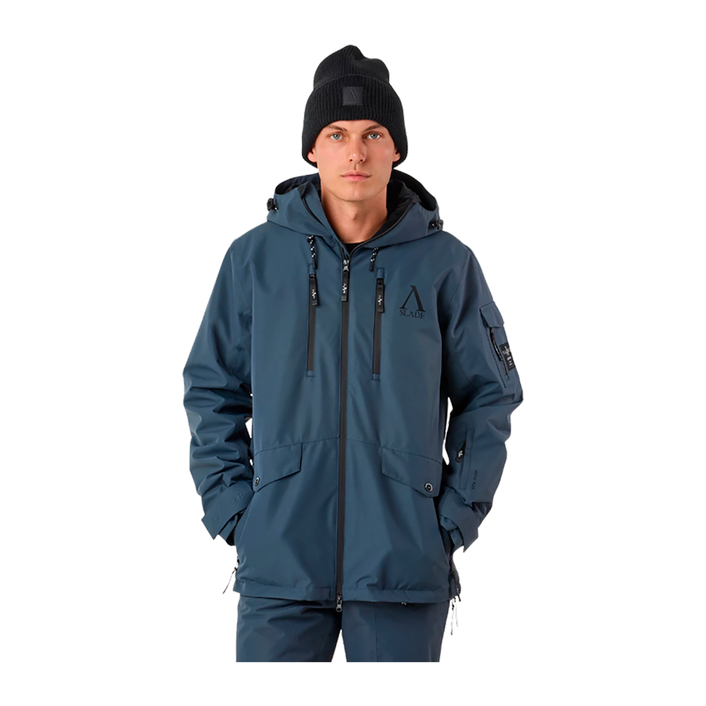På billedet ses en ung mand iført Slade Aspen Jacket II Sr, en alsidig herre vinter- og skijakke fra Slade. Jakken, i en formindskende blå farve, fremstår teknisk avanceret med dens mange funktionelle lommer og justerbare træk på hætte og talje. Den er designet til at modstå ekstreme vejrforhold, hvilket understreges af de vandtætte lynlåse og tapede sømme. Han bærer også en sort strikhue, som komplementerer det robuste vinterudstyr og tilføjer et ungdommeligt touch.