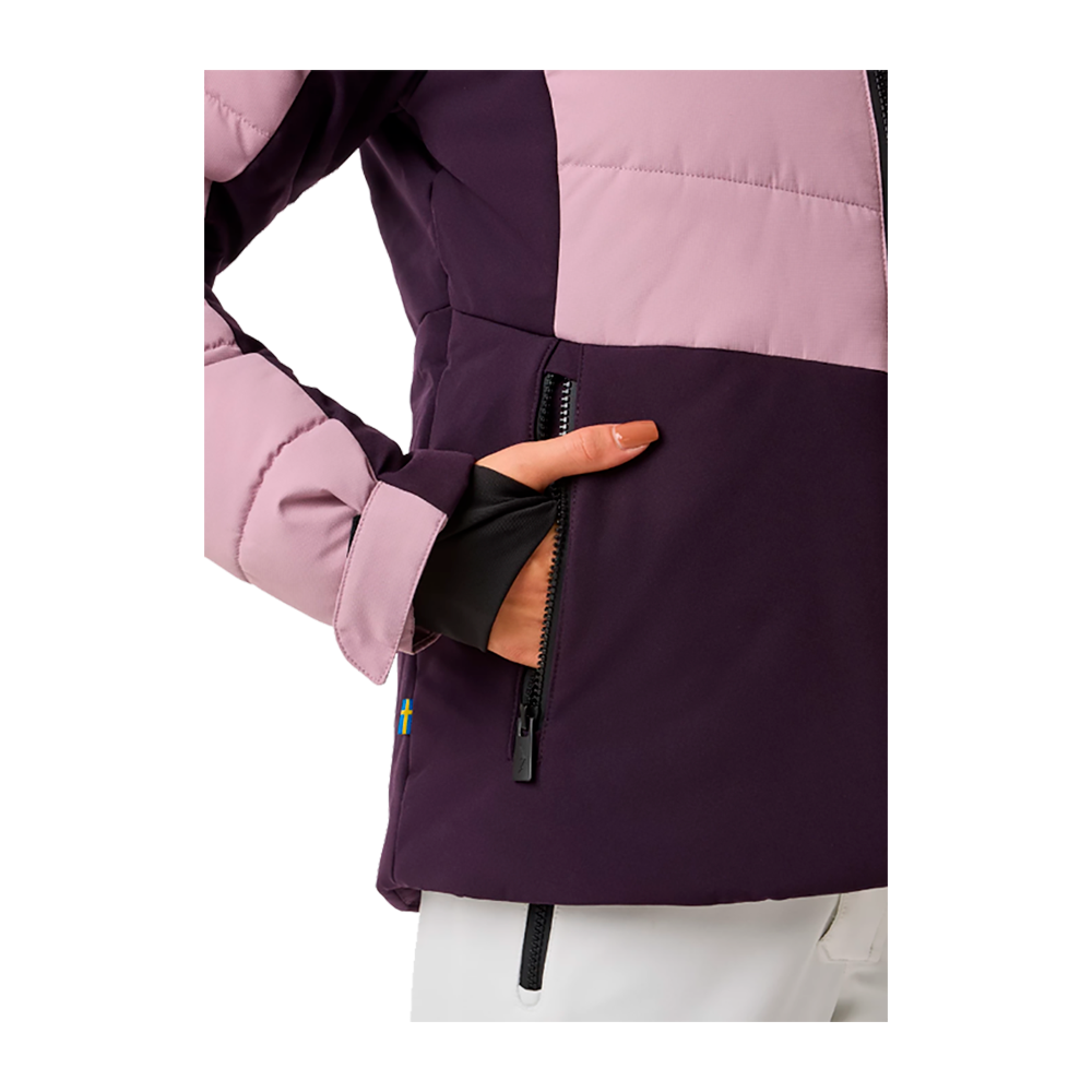 Denne Swedemount Vail Ski Jacket W er en stilfuld og funktionel dame skijakke, perfekt til vintersport. Jakken fremviser en blød rosa overdel og en mørk lilla nederdel, som begge er adskilt af en tydelig sort lynlås, der skaber et moderne look. Med sin justerbare hætte og robuste ydre holder den dig varm og tør under alle vejrbetingelser, mens de synlige lynlåslommer på siderne sikrer dine ejendele sikkert. En ideel ledsager til både skiløjperne og vinterlandskabet.